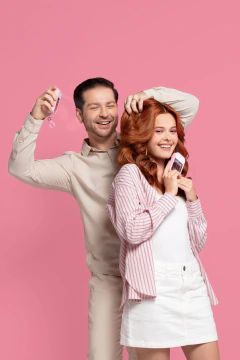 Homem e mulher sorrindo enquanto aplicam o Perfume Capilar Karina ft. Alan Vivian Floral Ambarado 45ml nos cabelos, com fundo rosa.