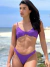 Biquíni conjunto Nina roxo em tecido texturizado, com top de alças fixas e aro inteiro, e calcinha asa delta, modelo posando na praia.