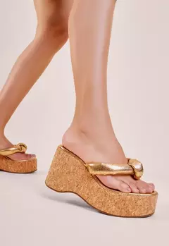 Tamanco plataforma dourado com salto alto de cortiça sendo usado em pé - Vicenza
