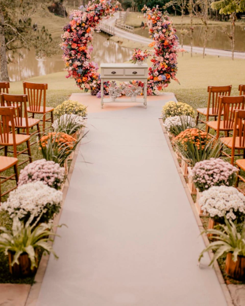 Decoração de casamento ao ar livre com tapete Linho Suss verde da coleção Placas, cercado por flores coloridas e cadeiras de madeira.