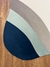 Tapete com bordas orgânicas em azul marinho, verde claro, taupe, off-white, bege gold e terracota sobre piso de madeira.