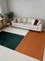 Tapete em tons de verde, terracota e off-white em uma sala de estar moderna com sofá claro e almofadas decorativas.