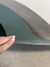 Detalhe do tapete Kurve® redondo em tons de verde e cinza, mostrando a flexibilidade do material, São José.