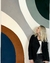 Mulher ao lado de tapete Kurve® em veludo com arcos nas cores azul marinho, terracota, off-white, granito e verde claro.