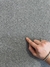 Mão apontando para a textura do tapete redondo de linho Cairo cinza, São José.