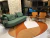 Tapete orgânico nas cores off-white, terracota e terra em sala com sofá verde e cadeiras de madeira.