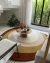 Tapete orgânico em nylon nas cores off-white, bege, mostarda e terracota, em uma sala de estar moderna com mesa de centro e plantas ao fundo, são José.