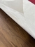 Detalhe do Tapete Optik com fundo off-white e borda sobre piso de madeira