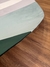 Detalhe do Tapete redondo com cores terracota, cobre, rosa gold, granito, off-white, verde claro e verde sobre piso de madeira, São José.