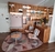 Tapete Optik orgânico com fundo nude rosado e detalhes em verde menta, granito, bege, rosé gold e creme em uma sala de estar moderna com móveis de madeira.