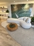 Sala moderna com sofá branco curvo, tapete Seed Bouclé Grécia Natural e Bouclé Capri Verde, mesa de centro de madeira e parede de mármore verde.