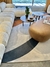 Tapete com bordas orgânicas em tons de Bouclé Capri Natural, Cinza, Terracota e Grafite, em uma sala de estar moderna com sofá e mesas de centro.