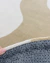 Close-up do tapete em nylon com bordas orgânicas nas cores off-white e trigo Econyl.