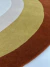 Tapete com design em curvas de cores off-white, bege, mostarda e terracota, feito de nylon Econyl, São José.