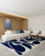Tapete em nylon nas cores off-white e azul marinho em uma sala moderna com sofá branco e decoração minimalista.