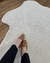 Tapete mesclado em nylon com bordas orgânicas em tons de off-white e bege claro sobre piso de madeira.