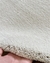 Tapete liso de nylon com bordas orgânicas na cor off-white, segurado por uma mão.