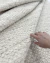 Tapete de fibra natural em off-white e bege, feito em tear manual, com uma mão tocando sua textura, Tapetes São José