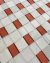 Detalhe do tapete sala redondo de 1,77 m, na cor off-white com detalhes alaranjados, da Coleção Trançado, mostrando textura em veludo e padrão geométrico trançado, Tapetes São José