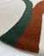 Tapete com bordas orgânicas nas cores off-white, terracota e verde escuro, feito de nylon Econyl.