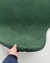 Tapete orgânico verde escuro sendo segurado por uma mão, feito de nylon Econyl.