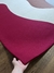 Tapete com design em cores granito, rosé gold, off-white e magenta sendo levantado por uma mão em um piso de madeira.