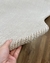 Detalhe do tapete mesclado de nylon com bordas orgânicas em off-white e bege claro.