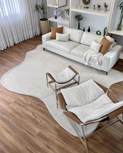 Tapete mesclado de nylon com bordas orgânicas em tons off-white e bege em uma sala de estar com sofá claro e cadeiras modernas.