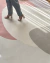 Pessoa caminhando sobre o Tapete Stone com design geométrico em tons nude, coral, bege e marrom claro, São José.