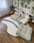 Sala de estar moderna com sofá Bouclé Capri em tons naturais, cinza e cappuccino, sobre tapete orgânico em madeira clara.