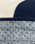 Detalhe do tapete Sea com textura Bouclé Capri Bege e Bouclé Atenas Azul Marinho, mostrando a parte inferior antiderrapante, São José.