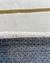 Detalhe do tapete em nylon, mostrando as cores off-white e mostarda, com base antiderrapante cinza.