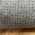 Close-up da textura antiderrapante do tapete Vênus com base antiderrapante cinza.
