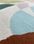 Detalhe do tapete em nylon com padrão colorido em tons de azul, verde, lilás e marrom.