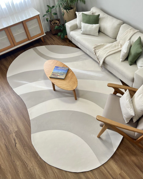 Tapete Kurve® com bordas orgânicas em tons off-white e natural, decorando uma sala de estar moderna com móveis em madeira clara.
