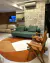Tapete com bordas orgânicas em Bouclé Capri Off-White e Terracota e Bouclé Atenas Terra em uma sala moderna com sofá verde e cadeiras de madeira, Tapetes São José