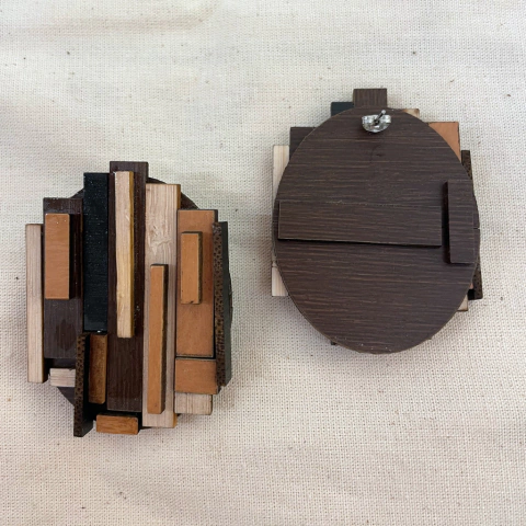 Brinco artesanal feito de pedaços de madeira em diferentes tonalidades, apresentando um design moderno e texturizado.