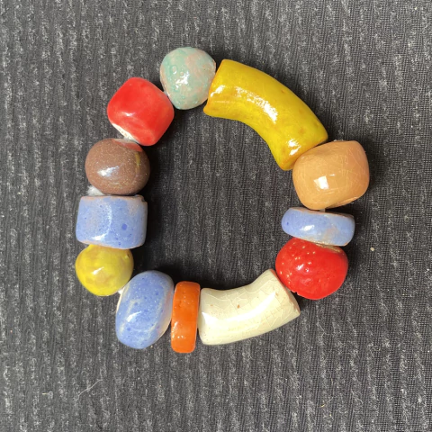 Pulseira de cerâmica com diversas contas coloridas dispostas em formato circular.