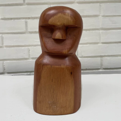 Escultura de madeira em forma de figura humana, com traços simplificados e acabamento liso.
