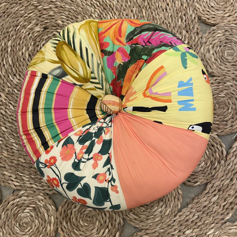 Almofada redonda colorida da marca Fuxicarte, com estampas vibrantes de flores e folhas.