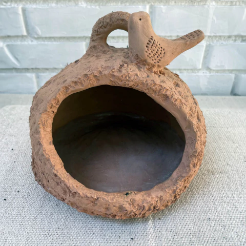 Vaso de barro em formato de cabaça com um pássaro esculpido na borda.
