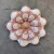 Flor de parede decorativa em cerâmica, com padrões em vermelho e branco, representando uma flor estilizada.