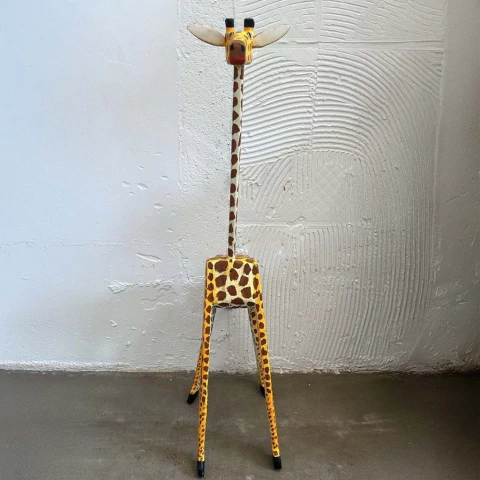 Estátua de girafa de madeira com detalhes em amarelo e marrom.