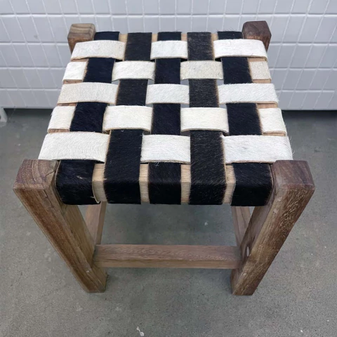 Banquinho de couro com assento trançado em preto e branco, estrutura de madeira.