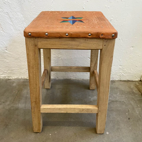 Banco de madeira com assento colorido e detalhes em metal, exibindo um padrão em forma de estrela.