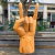 Escultura em madeira de mão fazendo sinal de "rock" com dedo indicador e mínimo levantados