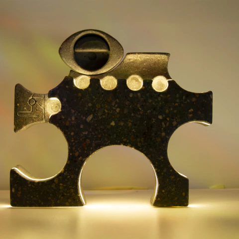 Escultura em pedra intitulada Vigilante por Robson Victor, com formato abstrato e detalhes arredondados iluminados em fundo neutro