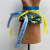Escultura em madeira de uma mão com pulseiras coloridas e fitas, representando a figa.