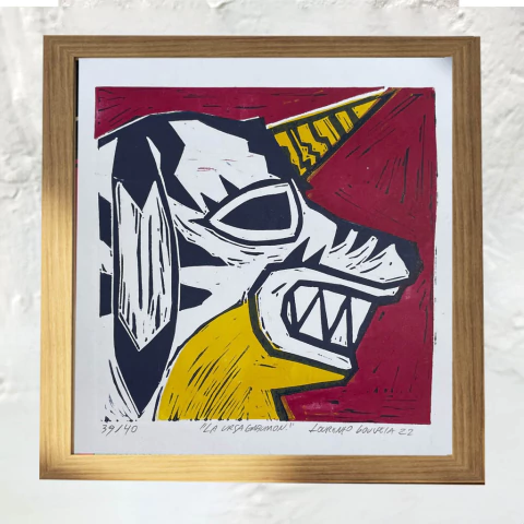 Gravura de La Ursa Gabumon, com traços em preto, amarelo e vermelho, emoldurada em uma moldura dourada.