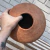 Vaso de cerâmica terracota com formato arredondado e bocal estreito, sobre um fundo de tecido listrado.